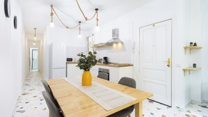 A modern kitchen with white cabinets, a wooden dining table, and a yellow vase.