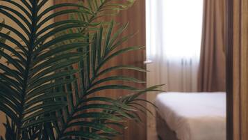 Una habitación con una cama, un armario de madera y una planta en maceta.