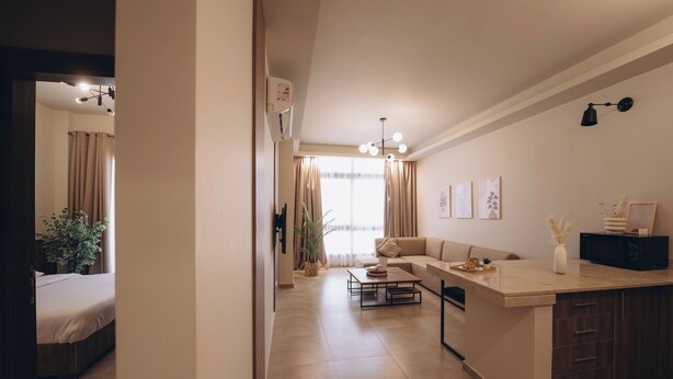 A modern living room with a sofa, a coffee table, and a kitchen area with a counter and cabinets. - Hazelspaces in New Cairo (New Cairo)
