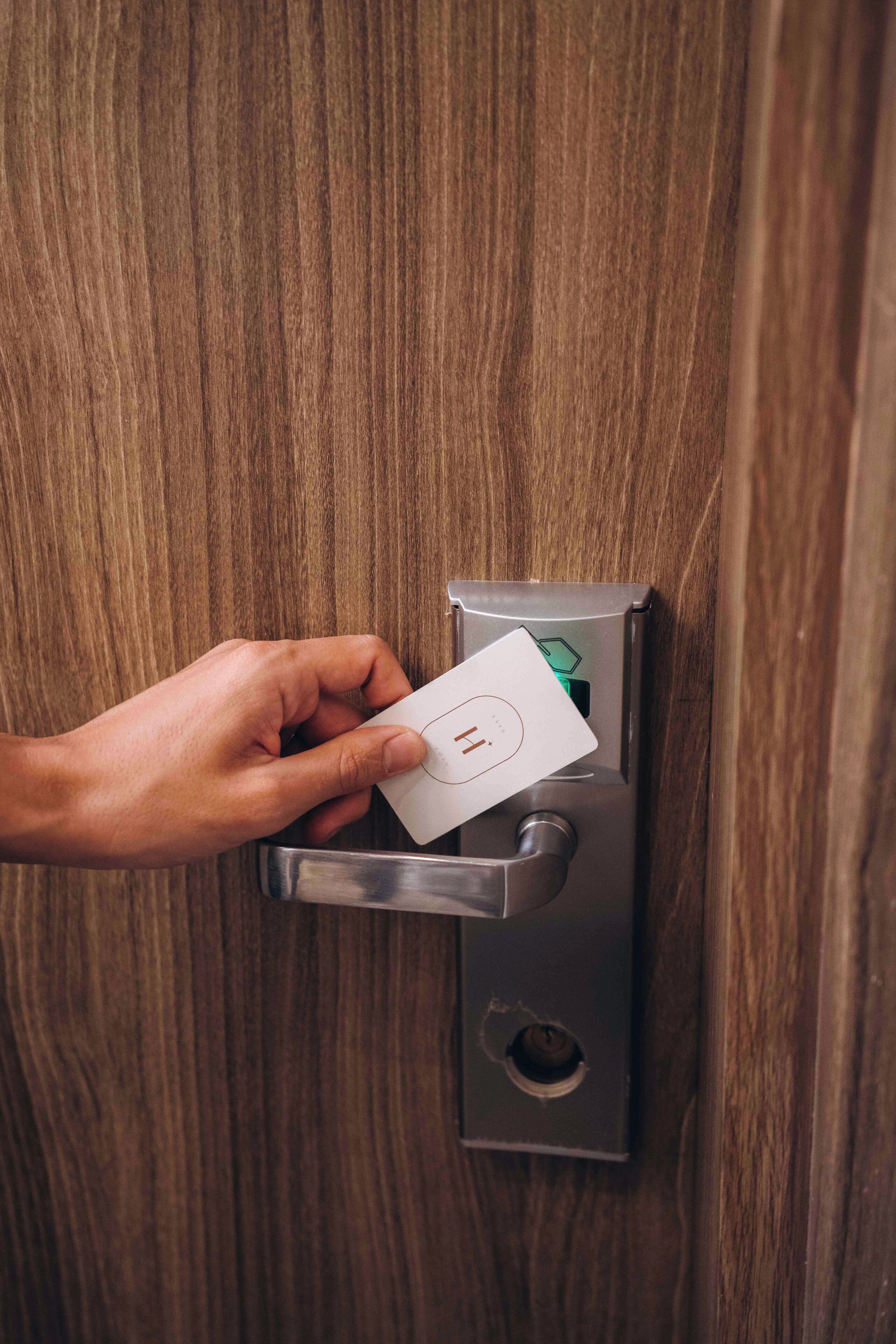 Une main insérant une carte dans le mécanisme de verrouillage d’une porte.