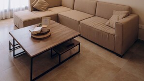 A modern living room with a beige sectional sofa, a wooden coffee table, and a ceiling light fixture. - Hazelspaces in New Cairo (New Cairo)