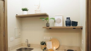 A compact kitchen with wooden cabinets, a stainless steel sink, a built-in stove, and a small shelf with decorative items. - Hazelspaces in New Cairo (New Cairo)