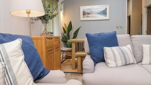 A living room with a sofa, a table, and a lamp. - 5 Waterside Wood (Windermere)