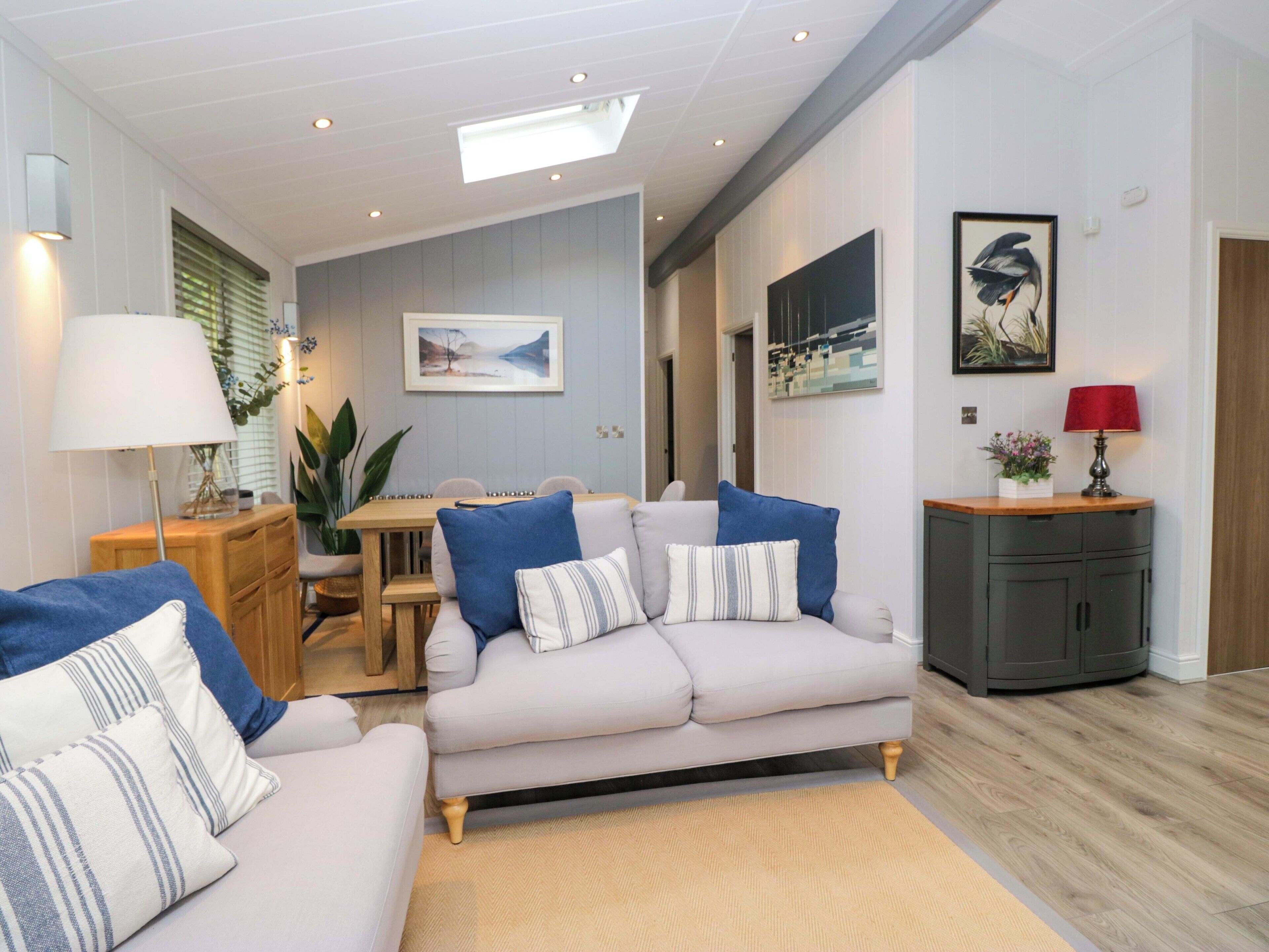 A living room with a sofa, a dining table, and a kitchen area.