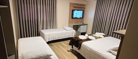 A hotel room with two single beds, a TV on the wall, and a wooden ceiling.