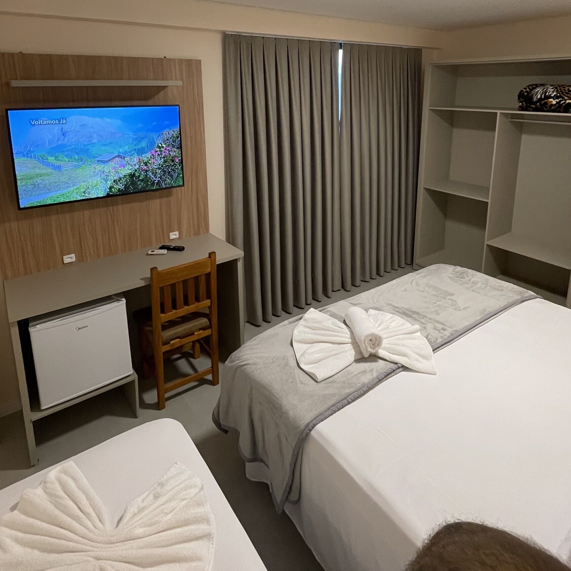 A hotel room with a bed, a desk, a television, and a chair.