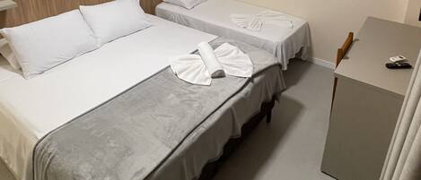 A hotel room with two beds, a bedside table, a desk, and a wall-mounted air conditioner.