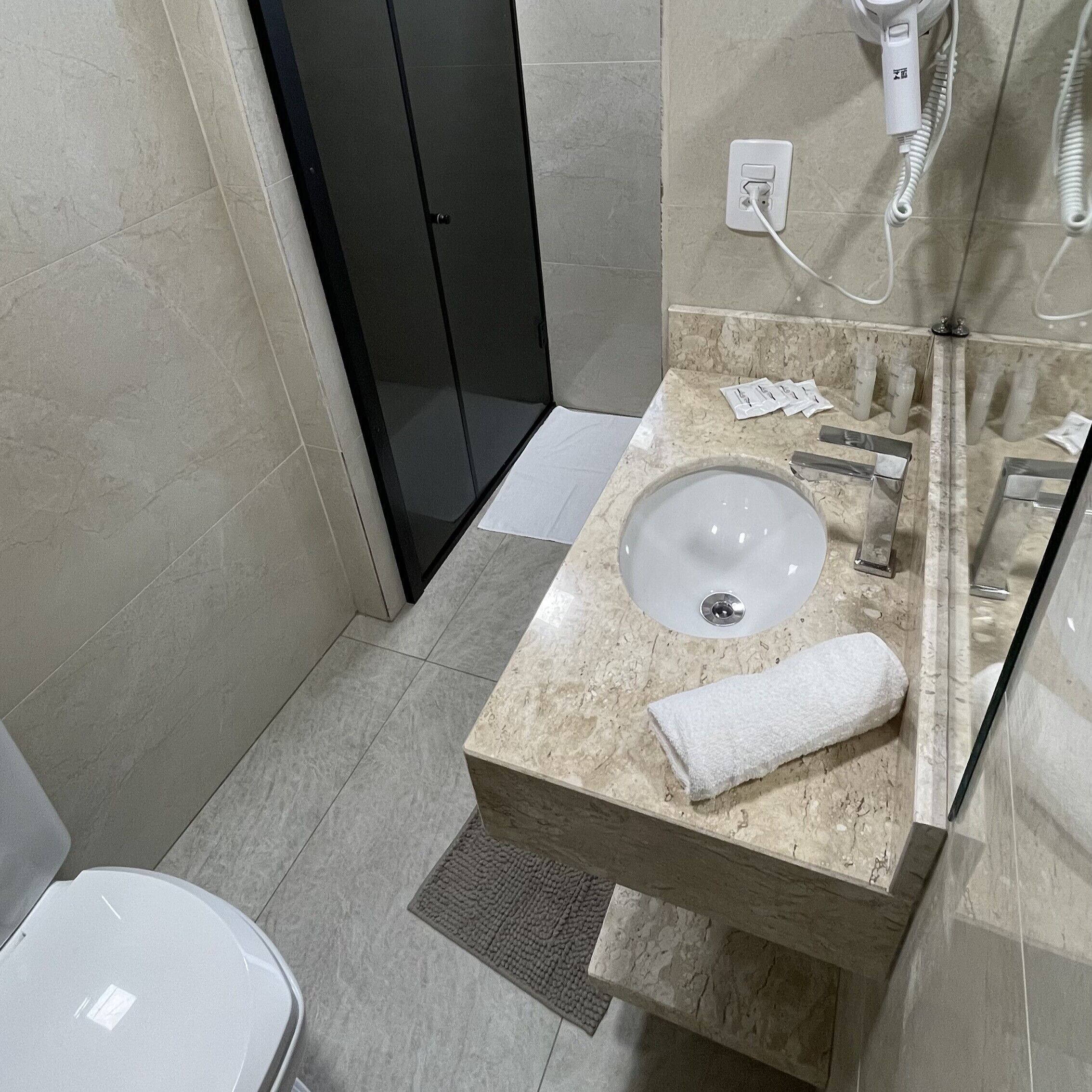 Baño con lavabo, espejo, toalla y zona de ducha.