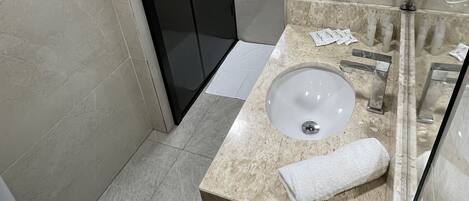 Baño con lavabo, espejo, toalla y zona de ducha.