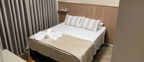 Une chambre d’hôtel avec un lit, une table de chevet, un climatiseur fixé au mur et un rideau.