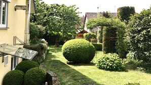 A garden with a pathway, neatly trimmed bushes, and a small pond. - Apartment 'Holiday Apartment, 60 sqm' with Balcony and Wi-Fi (Ammerbuch)