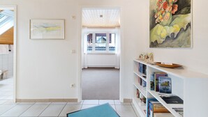 A hallway with a bookshelf, a framed painting, and a view to a balcony. - Apartment 'Holiday Apartment, 60 sqm' with Balcony and Wi-Fi (Ammerbuch)