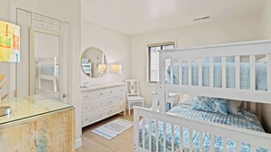 A child's bedroom with a bunk bed, a dresser, a mirror, and a window with blinds. - Silver Sun 201 (Ocean City)