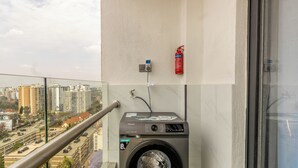 A balcony with a washing machine, a fire extinguisher, and a power outlet.