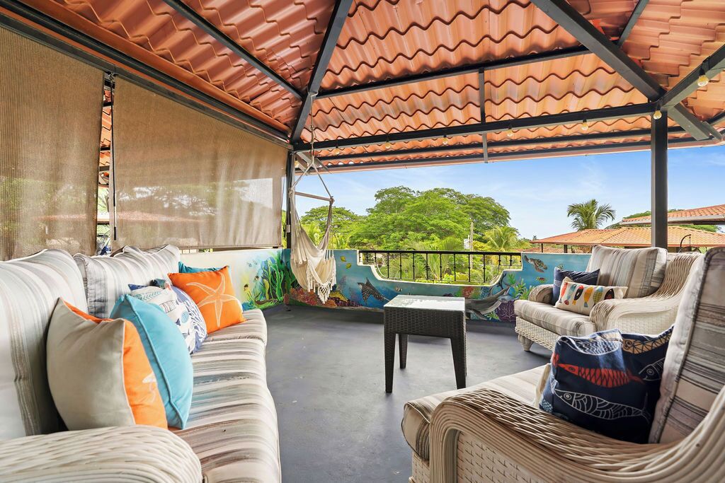 Un espace extérieur aménagé avec un patio couvert, des canapés confortables et une table.