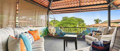 An outdoor seating area with a covered patio, cushioned sofas, and a table.