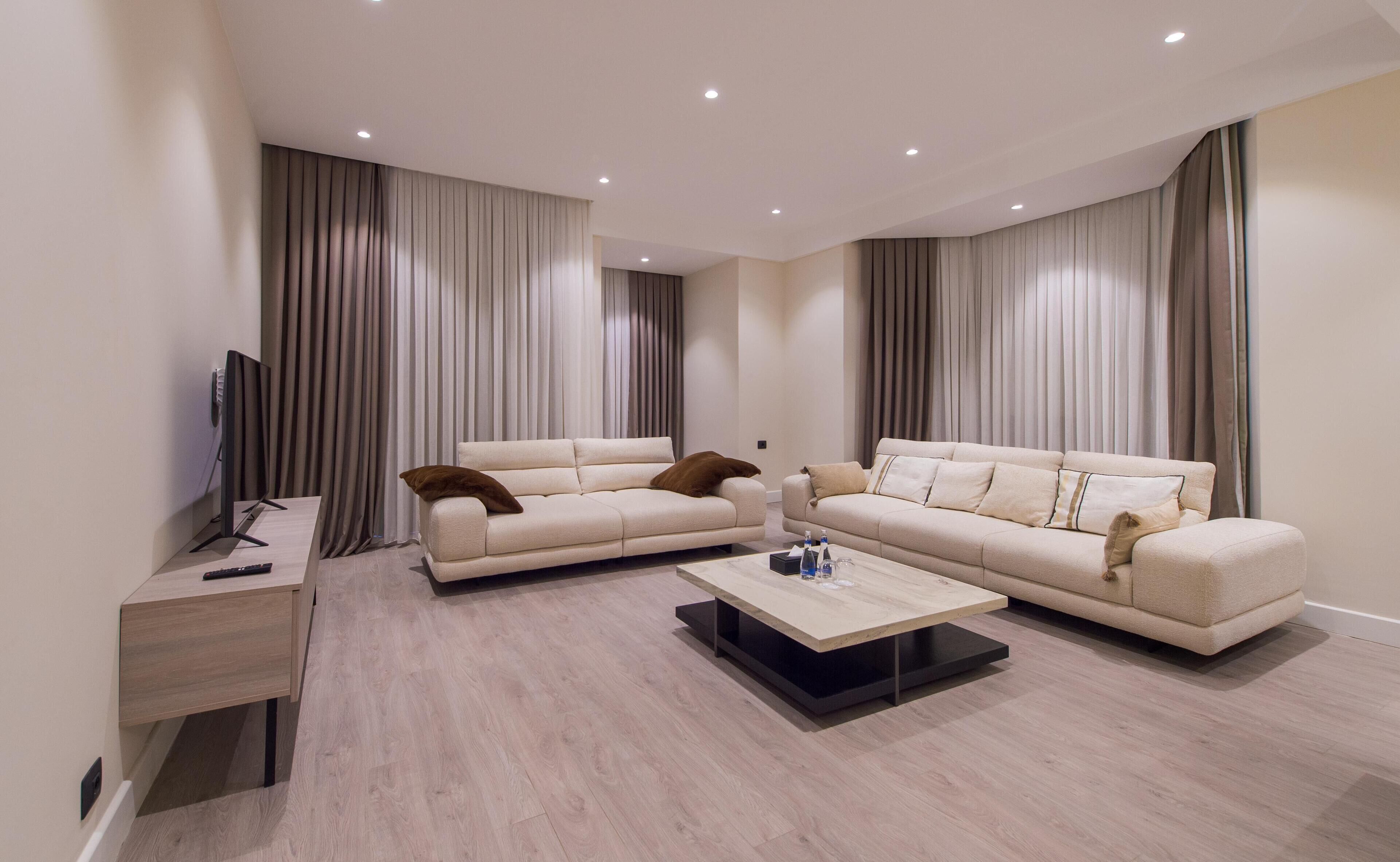 A modern living room with two sofas, a coffee table, and a TV on a stand.
