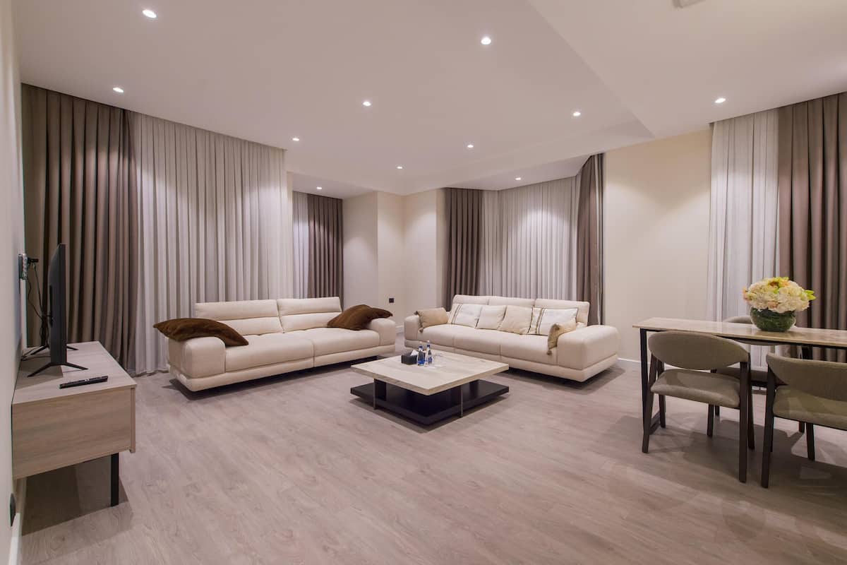 Ein modernes Wohnzimmer mit einer Sofagarnitur, einem Couchtisch, einem Fernseher und einem Essbereich mit Stühlen und Tisch.