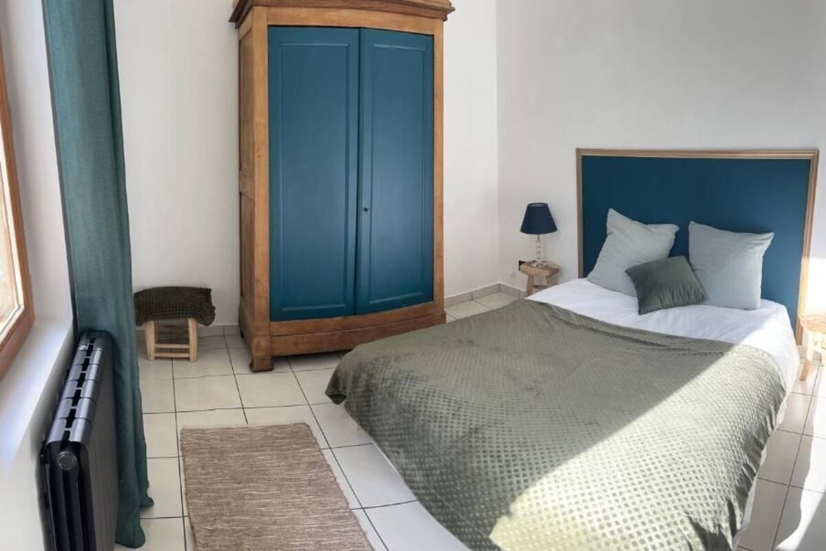 A bedroom with a bed, a wooden wardrobe, a nightstand, and a radiator.
