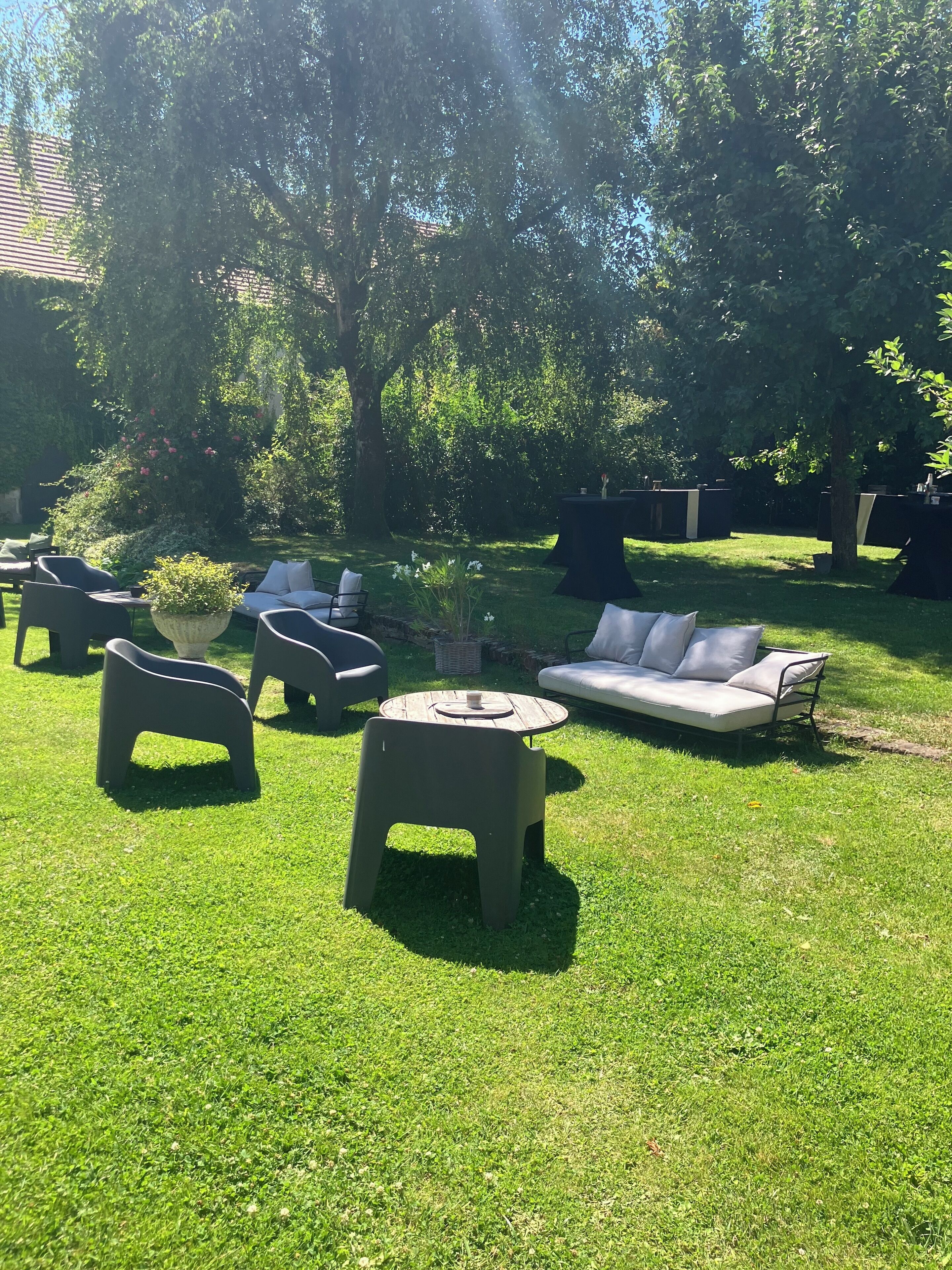 Un área de estar al aire libre con césped, un sofá y dos sillones.