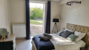 A bedroom with a bed, a lamp, a radiator, and a view of the outdoors. - La ferme de Valeuse (Morienval)