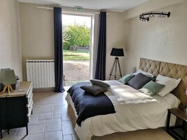 Quarto com cama, luminária, radiador e vista para o exterior.