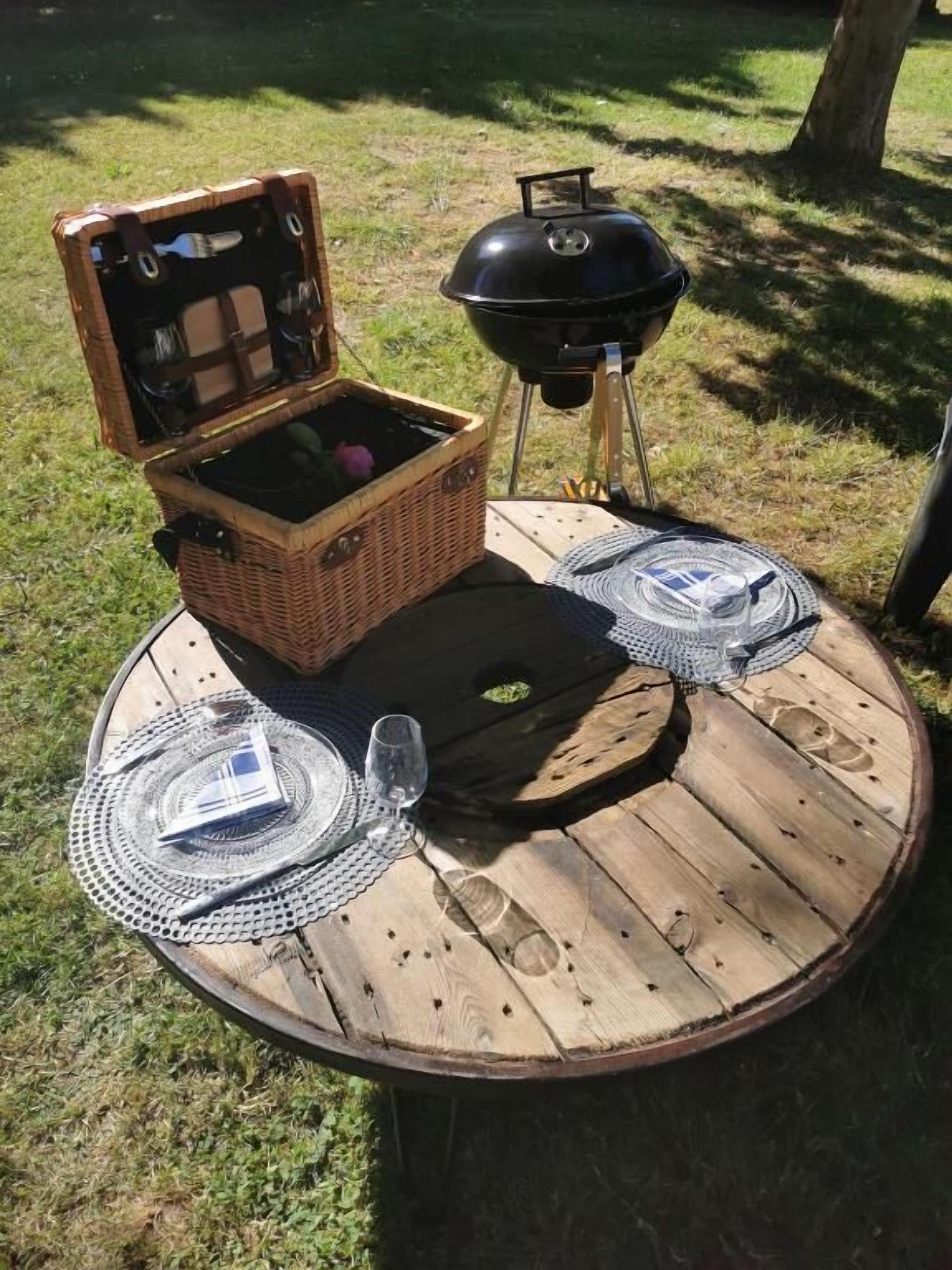 Une table ronde en bois, sur laquelle sont posés un panier en osier et un ensemble de grilles noires.