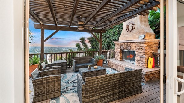 Une terrasse extérieure aménagée avec des meubles en osier, une cheminée en pierre et une pergola.