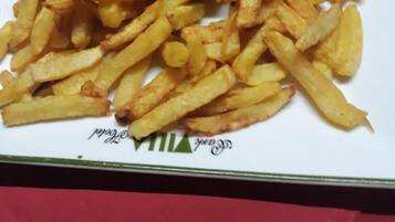 Un plato de comida con papas fritas, salchichas y una pequeña ensalada.