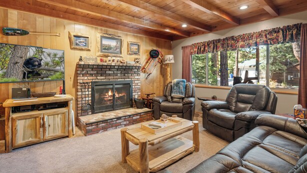 A cozy living room with a fireplace, leather furniture, and wooden beams on the ceiling. - All in Cabin (Big Bear Lake)