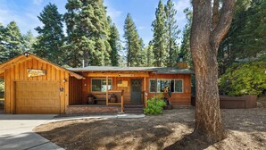 A rustic cabin with a wooden exterior, a front porch, and a garage. - All in Cabin (Big Bear Lake)