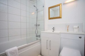 A bathroom with a glass-enclosed shower, a white sink with a mirror above it, and a toilet. - Vacant Nests | High Quay View | Wi-Fi (Tyne and Wear)