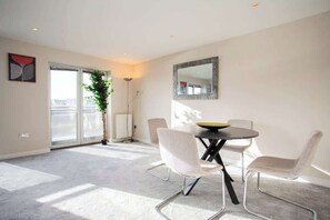 A modern living room with a dining table, four chairs, a large mirror, and a potted plant. - Vacant Nests | High Quay View | Wi-Fi (Tyne and Wear)