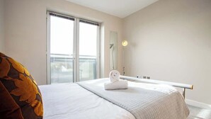 Una camera d'albergo con un letto, una finestra, uno specchio e un asciugamano.