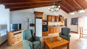 A spacious living room with wooden furniture, a television, and a chandelier. - Casa Café - Rural charm with all the comforts of home (Los Realejos)