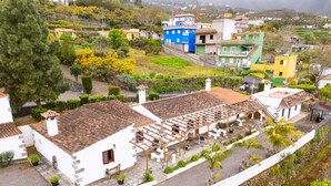 A traditional white building with a tiled roof, a stone wall, and a small garden area with potted plants. - Casa Café - Rural charm with all the comforts of home (Los Realejos)
