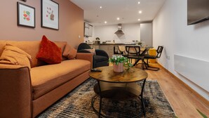 A living room with a sofa, a coffee table, and a dining area with chairs and a table. - Spacious City Apartment| 2 bd/2 bth| Free Parking (Merseyside)