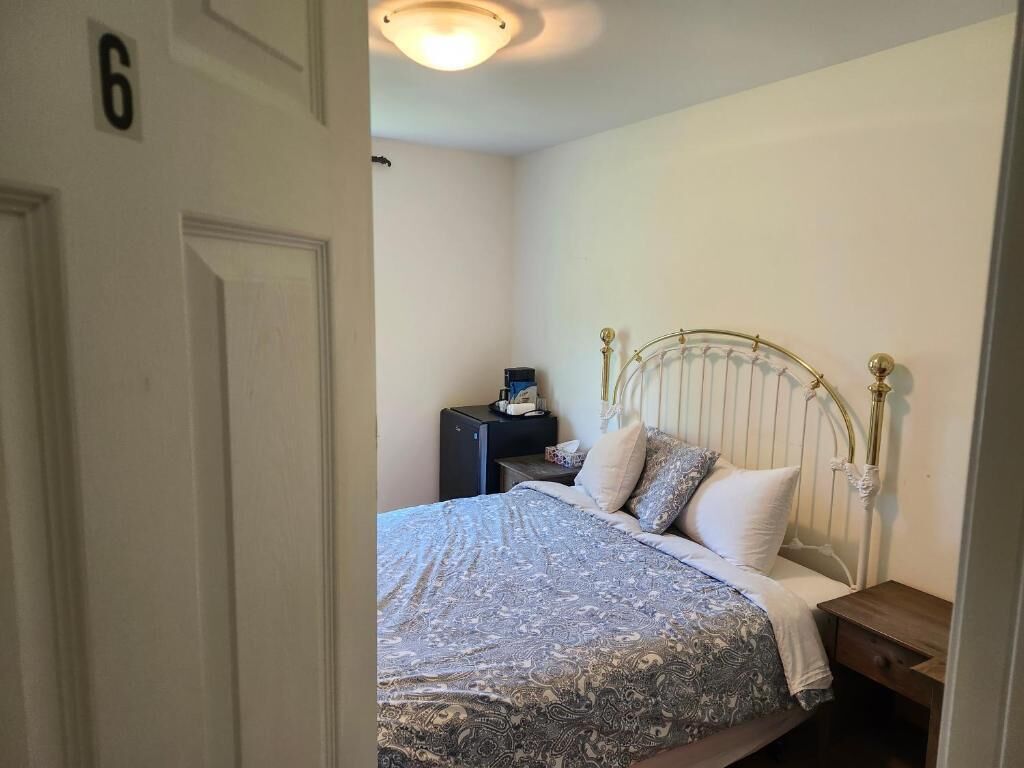 Un dormitorio con cama, mesita de noche y lámpara de pared.