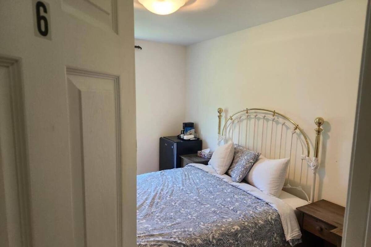 Un dormitorio con cama, mesita de noche y lámpara de pared.