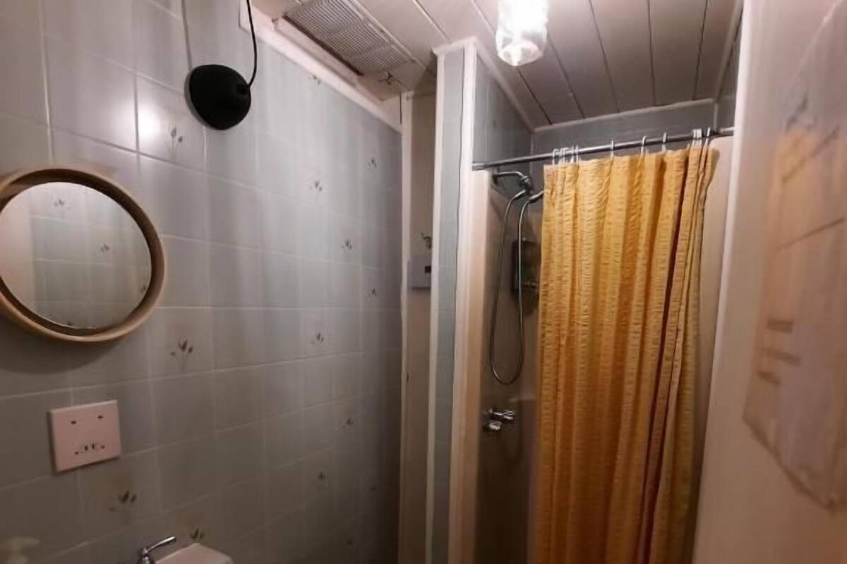 A bathroom with a sink, mirror, shower curtain, and a light fixture.