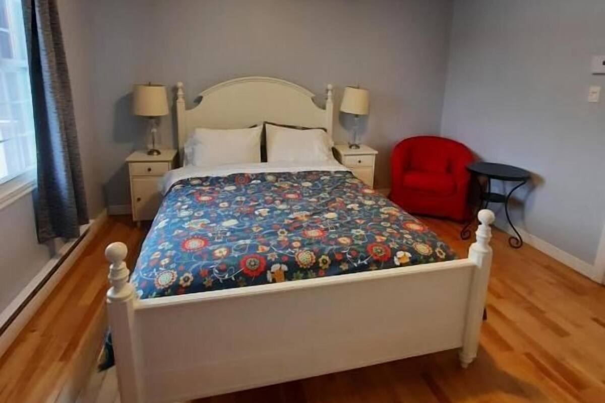 A bedroom with a bed, bedside tables, a red chair, and a small table.