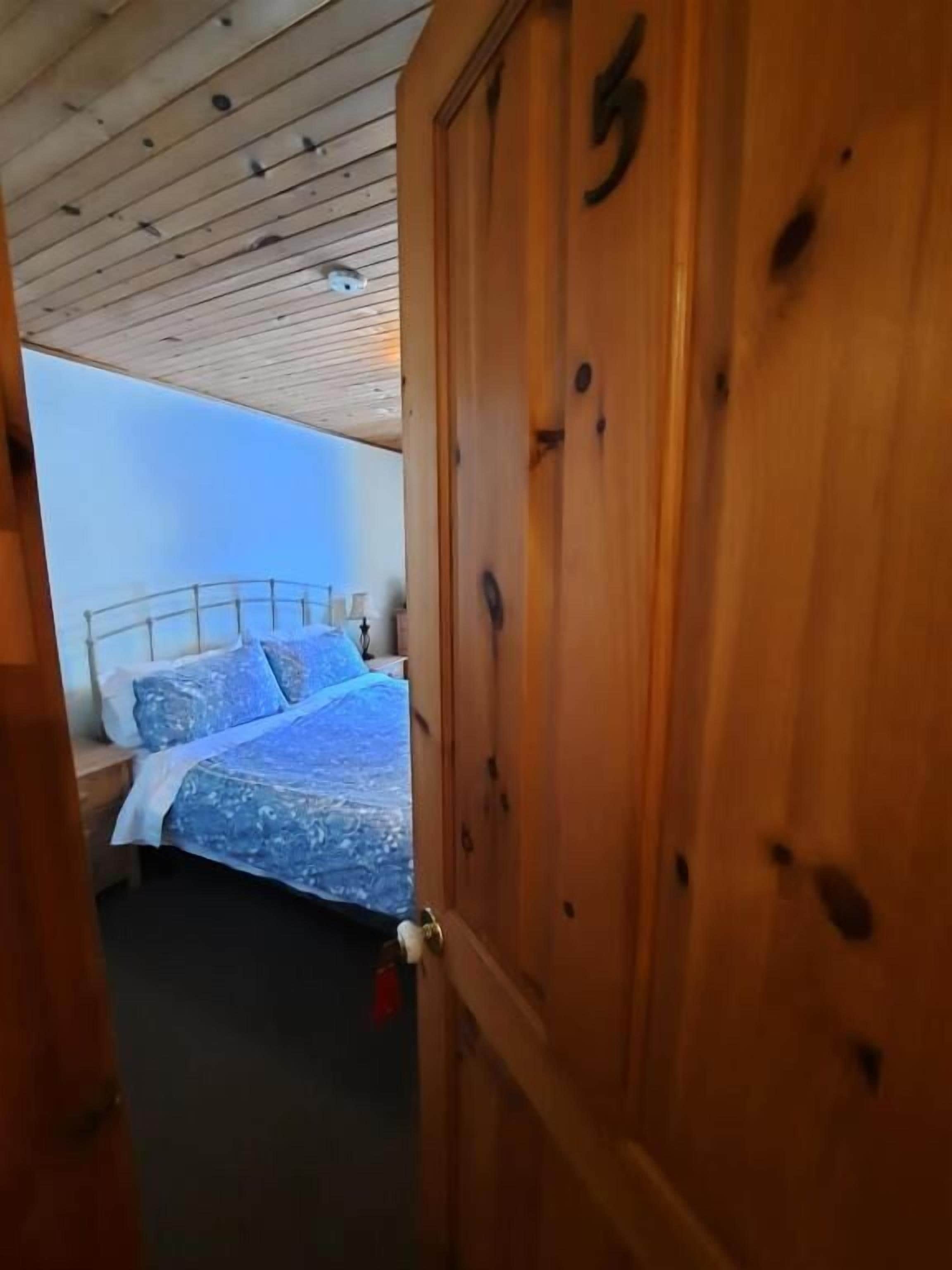Una puerta de madera con el número 5 y una cama con una colcha azul estampada.