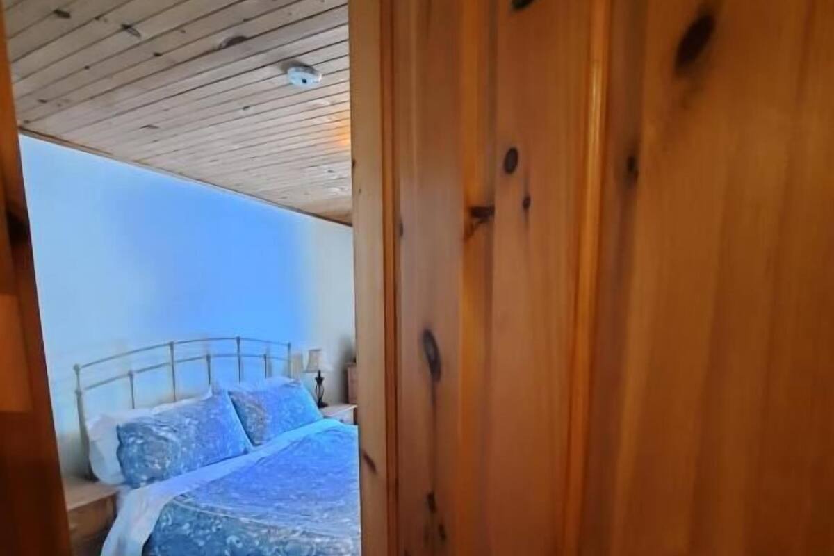 Una puerta de madera con el número 5 y una cama con una colcha azul estampada.