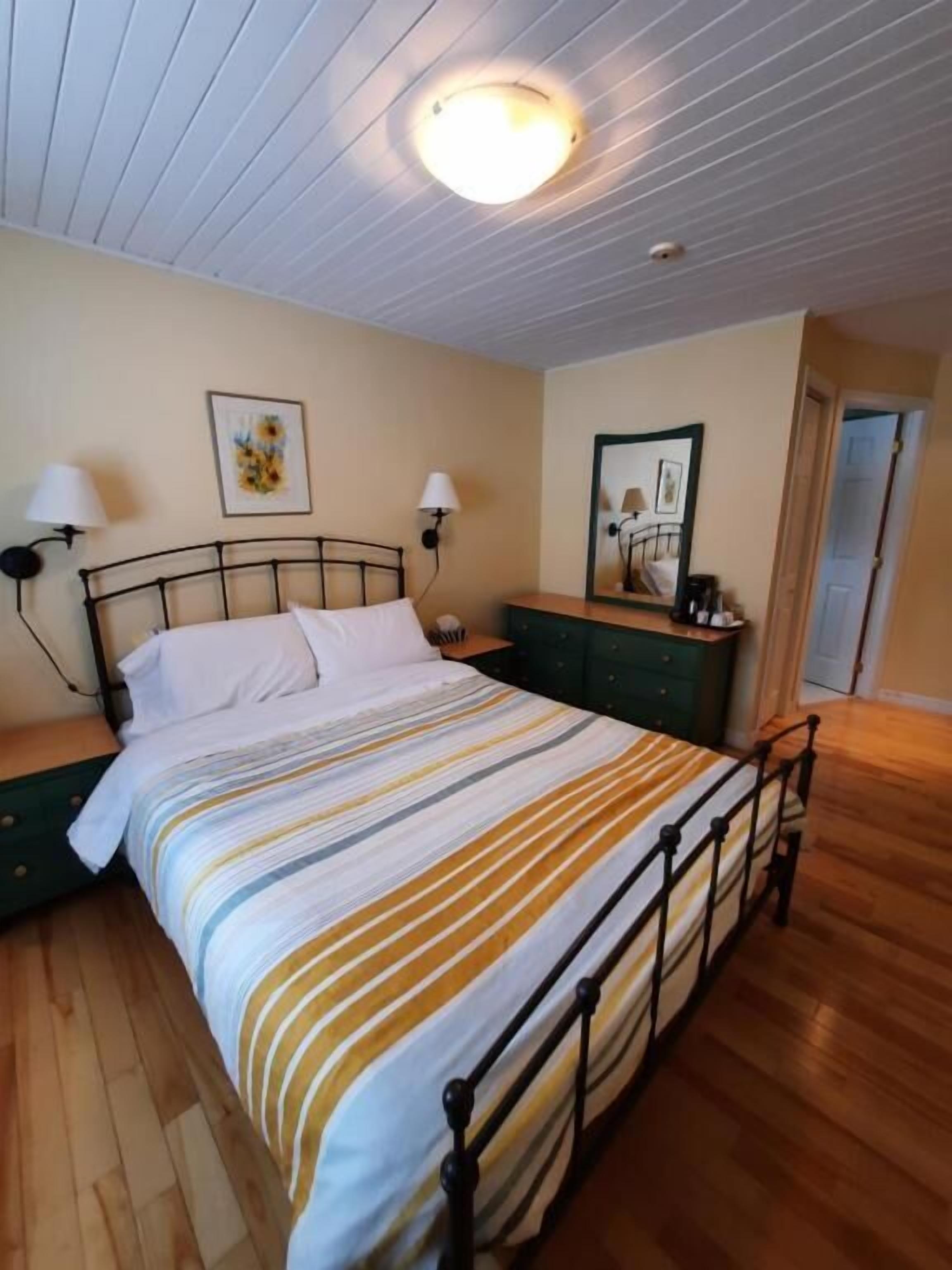 A bedroom with a bed, bedside lamps, a nightstand, a dresser, and a ceiling light fixture.