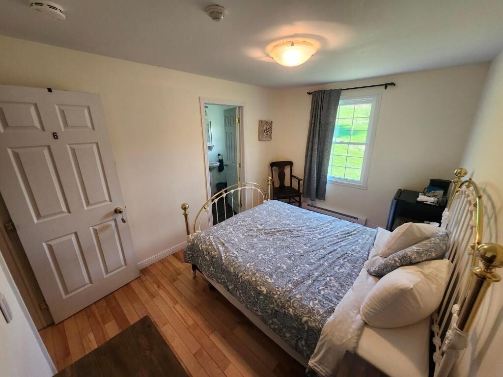 A bedroom with a bed, a door, a window, and a chair.