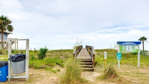 A wooden boardwalk leading to a beach area with a sign indicating public beach access.
