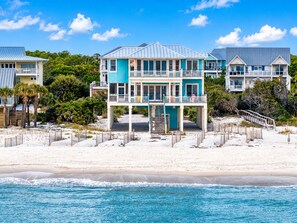 A beachfront property with a two-story house featuring a balcony and a covered walkway. - Sunrise Point - Beach Front, Pet Friendly, Community Pool, Biking Trails! (St. George Island)