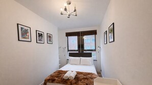 A bedroom with a bed, a chandelier, and framed pictures on the walls. - Central London 2BR Near Piccadilly Circus for 4 (London)