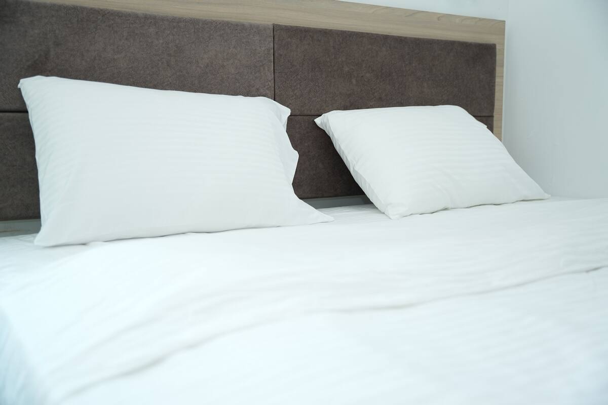 A bed with white bedding and two white pillows.