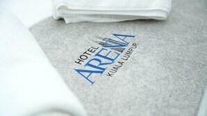 Une serviette pliée sur laquelle est imprimé le texte « HÔTEL ARENA KUALA LUMPUR ».